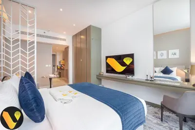 a bedroom with a large bed and a tv on a wall at Vogue Business Bay Damac Maison Prive near Burj Khalifa and Dubai Mall, Studio Apartment with Balcony, Canal and City view, Access to all Amenities in Dubai