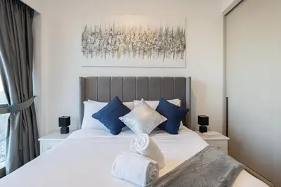 a bedroom with a bed with blue and white pillows at Stay in the #1 Burj & Fountain View 4BR Apartment in Dubai