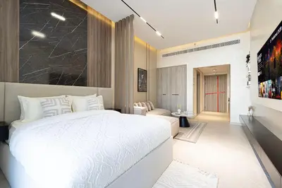 a bedroom with a white bed and a living room at Modern & Luxurious Studio - Near CircleMall in Dubai