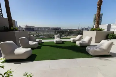a group of white chairs sitting on a green carpet at Elegant 1BR in JVC in Dubai