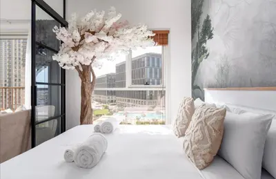 a bedroom with a white bed with a tree at 2 bedroom apartment Dubai Hills in Dubai