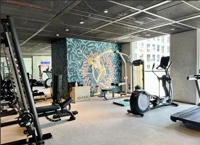 a gym with several tread machines and a mural at 2 bedroom apartment Dubai Hills in Dubai