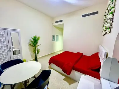 a bedroom with a red bed and a table and chairs at Haifa building in Dubai