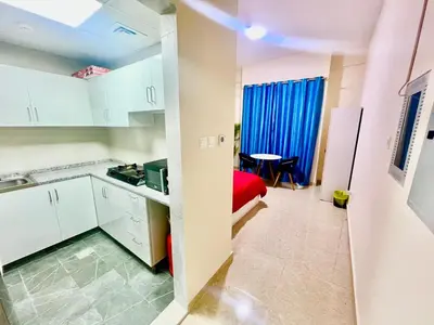 a kitchen with white cabinets and a red bed in a room at Haifa building in Dubai