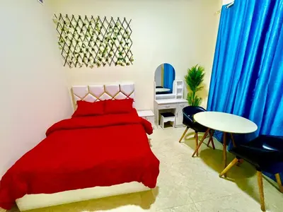 a bedroom with a red bed and a table and chairs at Haifa building in Dubai