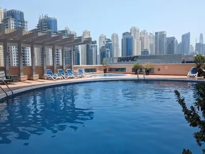a large swimming pool with chairs and a city skyline at Big Studio Apartment in Dubai Marina Walking to JBR Beach, Cruise and DMCC Metro in Dubai