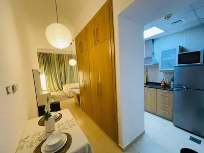 a kitchen with a table and a refrigerator at Big Studio Apartment in Dubai Marina Walking to JBR Beach, Cruise and DMCC Metro in Dubai