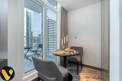 a dining room with a table and chairs and a large window at Vogue Business Bay Damac Maison Prive near Burj Khalifa and Dubai Mall, Studio Apartment with Balcony, Canal and City View, Access to all Amenities in Dubai