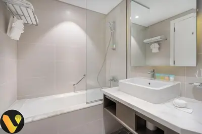 a white bathroom with a sink and a shower at Vogue Business Bay Damac Maison Prive near Burj Khalifa and Dubai Mall, Studio Apartment with Balcony, Canal and City View, Access to all Amenities in Dubai