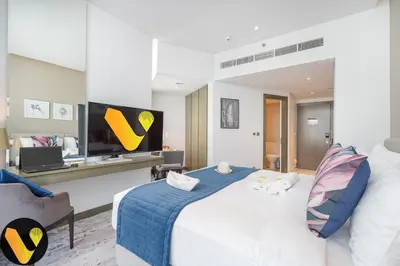 a bedroom with a large white bed and a tv at Vogue Business Bay Damac Maison Prive near Burj Khalifa and Dubai Mall, Studio Apartment with Balcony, Canal and City View, Access to all Amenities in Dubai