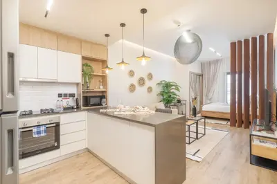 an open kitchen with white cabinets and a large island at Smartly Designed Studio in JVC in Dubai