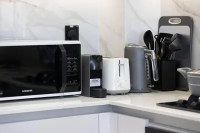 a kitchen counter with a microwave and other appliances at Binghatti House in JVC - New Apartment in Dubai
