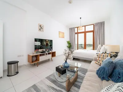 a white living room with a couch and a tv at Chic Waterfront Studio in Palm Views West in Dubai
