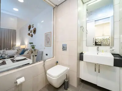 a white bathroom with a toilet and a sink at Chic Waterfront Studio in Palm Views West in Dubai