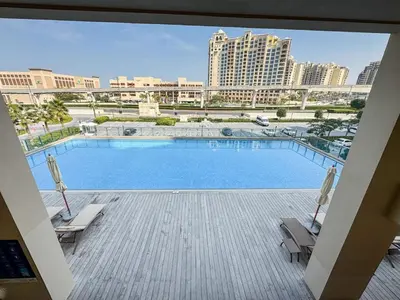 a large swimming pool with two chairs and a building at Chic Waterfront Studio in Palm Views West in Dubai