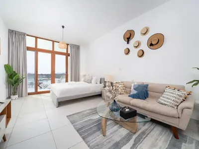 a white living room with a couch and a bed at Chic Waterfront Studio in Palm Views West in Dubai