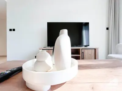 a living room with a white vase on a table at Deluxe 2-Bedroom Apartment - JVC Binghatti Emerald in Dubai