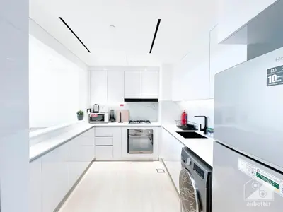 a white kitchen with white cabinets and a dishwasher at Deluxe 2-Bedroom Apartment - JVC Binghatti Emerald in Dubai