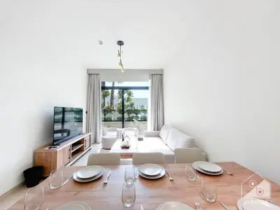 a living room with a table with chairs and a television at Deluxe 2-Bedroom Apartment - JVC Binghatti Emerald in Dubai