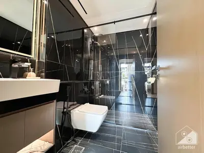 a bathroom with a toilet and a shower with black tiles at Deluxe 2-Bedroom Apartment - JVC Binghatti Emerald in Dubai