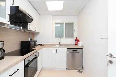 a kitchen with white cabinets and a sink at Stylish 1-Bedroom with Breathtaking Views at Dubai Marina in Dubai