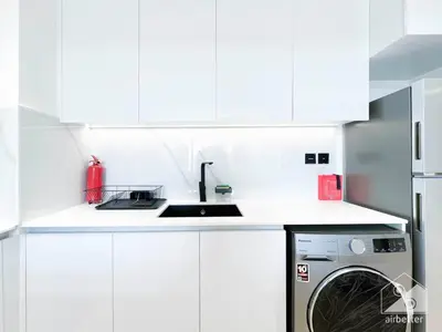 a white kitchen with a sink and a dishwasher at Elegant 2 Bedroom Apartment -Binghatti Emerald JVC in Dubai