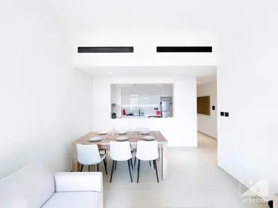 a dining room with a wooden table and white chairs at Elegant 2 Bedroom Apartment -Binghatti Emerald JVC in Dubai