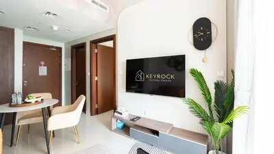 a living room with a table and a clock on a wall at Keyrock Living - Luxury 1BR with Lake View at Reva in Dubai