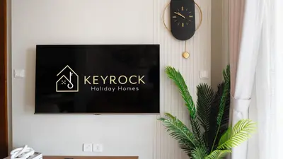 a tv on a wall with a keyrock holiday homes sign at Keyrock Living - Luxury 1BR with Lake View at Reva in Dubai