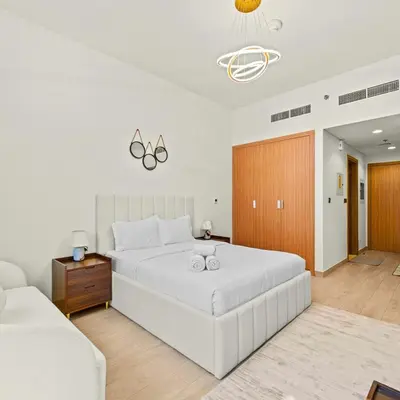 a bedroom with a large white bed and a couch at Azizi Riviera 35 - Studio with full Kitchenet - Ideal for monthly in Dubai