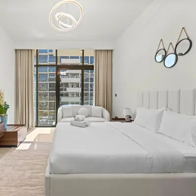 a white bedroom with a large bed and a large window at Azizi Riviera 35 - Studio with full Kitchenet - Ideal for monthly in Dubai