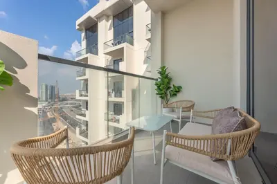 a balcony with two chairs and a table on a building at StayShort - Sleek Studio in Jumeirah Village Triangle in Dubai