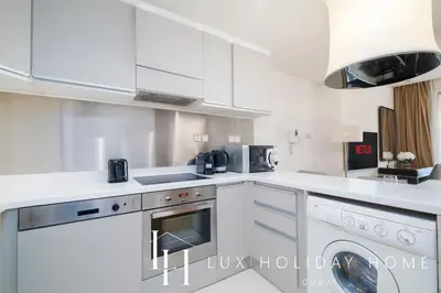 a kitchen with white cabinets and a washer and dryer at LUX The EMAAR Fashion Avenue Studio 2 in Dubai