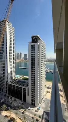 a view of two tall buildings with a crane at Seaside Elegance 1BR at Emaar Beachfront in Dubai