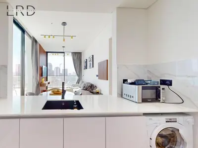 a white kitchen with a washer and a microwave at Modern Smart Home 2BR with Private Pool in JVC in Dubai