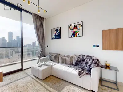 a living room with a white couch and a large window at Modern Smart Home 2BR with Private Pool in JVC in Dubai
