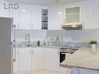 a white kitchen with white cabinets and a sink at Stylish 2BR Apartment Steps from Metro and Marina Mall in Dubai
