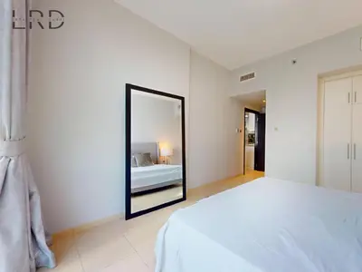 a bedroom with a white bed and a mirror at Stylish 2BR Apartment Steps from Metro and Marina Mall in Dubai