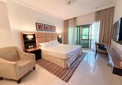 a bedroom with a bed and a chair and a television at Capital Bay Tower B Comfort Studio in Dubai