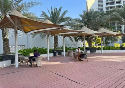 two people sitting at tables under umbrellas on a patio at Capital Bay Tower B Comfort Studio in Dubai