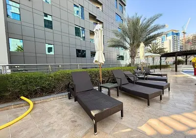a patio with tables and chairs and an umbrella at Capital Bay Tower B Comfort Studio in Dubai