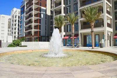 a fountain in front of a building with palm trees at Knokey Dubai Creek Beach with Lagoon Pool access in Dubai