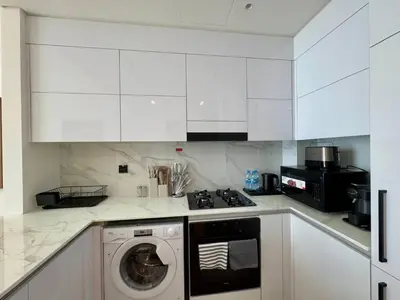 a kitchen with white cabinets and a washing machine at Modern 1br In Jvc Balcony, Pool & Parking in Dubai