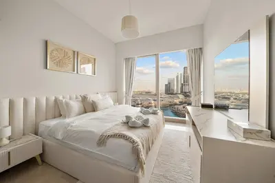 a white bedroom with a large bed and a large window at FIRST CLASS 2BR Burj Khalifa & Fountain view in Dubai