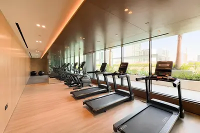 a row of treadmills in a gym with windows at GuestReady - Sky-High Luxury with a Private Pool in Dubai