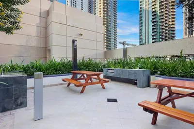 two picnic tables in front of a building with tall buildings at FIRST CLASS 2BR Spectacular Fountain Views in Dubai