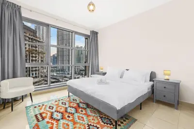 a bedroom with a white bed and a large window at FIRST CLASS 2BR Spectacular Fountain Views in Dubai
