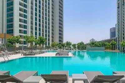 a large swimming pool with chairs and blue water at 2 bedroom apartment infront of Dubai mall by Aventine homes in Dubai