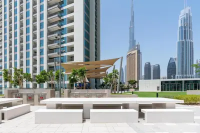 a park with tables and benches in front of a city at 2 bedroom apartment infront of Dubai mall by Aventine homes in Dubai