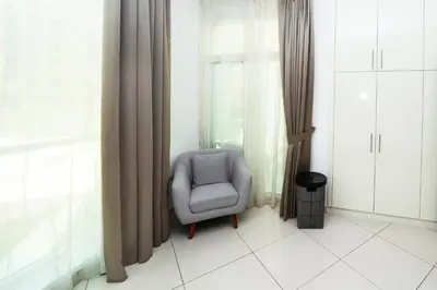 a chair sitting in a room with curtains at 2 Bed in Atlantic Tower 2 by PK Holidays in Dubai